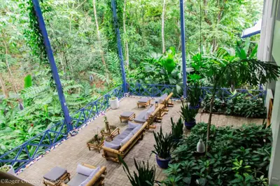 a patio with loungers and chairs and plants at Hotel Plaza Yara in Manuel Antonio
