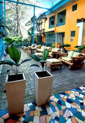 a patio with chairs and potted plants and a building at Hotel Plaza Yara in Manuel Antonio