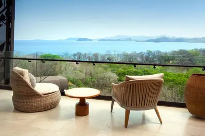 a patio with chairs and a table and a view of the ocean at W Costa Rica Resort – Playa Conchal in Playa Conchal