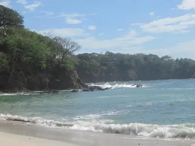 a beach with a bunch of waves in the ocean at Plumita Pacifica in Playa Junquillal