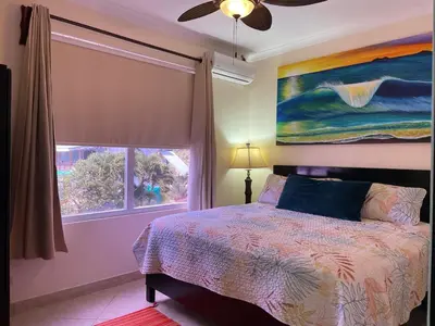 a bedroom with a bed and a large window at Surf Inn Hermosa in Playa Hermosa