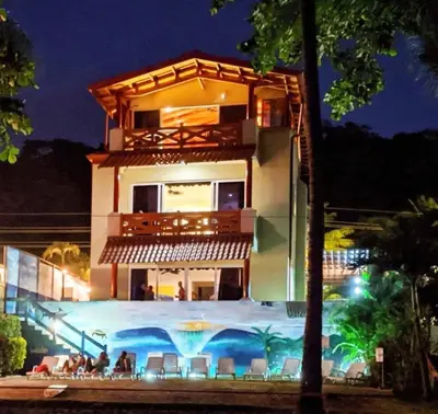 a building with a swimming pool in front of it at Surf Inn Hermosa in Playa Hermosa
