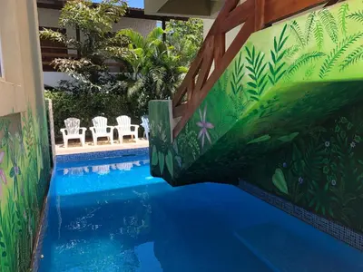 a swimming pool with chairs and a painting on the wall at Surf Inn Hermosa in Playa Hermosa