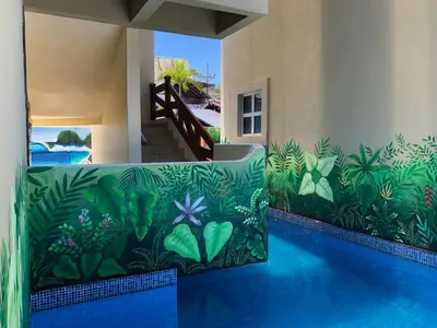a swimming pool with a mural of plants on the side of a house at Surf Inn Hermosa in Playa Hermosa