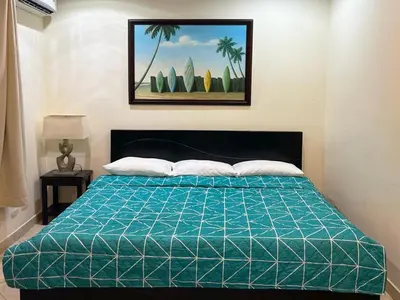 a bed with a green comforter in a bedroom at Surf Inn Hermosa in Playa Hermosa