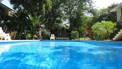 a large blue swimming pool with trees in the background at Coco Beach Home in Coco