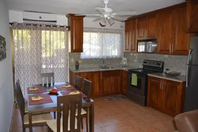a kitchen with wooden cabinets and a table with a dining room at Coco Beach Home in Coco