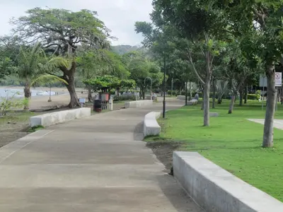 a park with a sidewalk and trees and a beach at Coco Beach Home in Coco