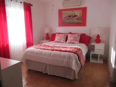 a bedroom with a bed with red curtains and red pillows at Coco Beach Home in Coco