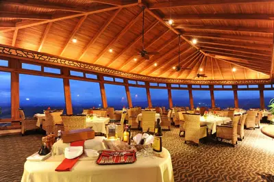 a restaurant with white tables and chairs with a view at The Springs Resort & Spa at Arenal in Fortuna