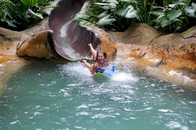a young child playing on a slide in the water at The Springs Resort & Spa at Arenal in Fortuna