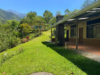 a house with a grass yard next to a building at Hotel Uran in Rivas