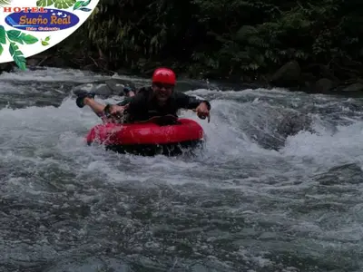 a man in a red raft in a river at Hotel SueñoReal RioCeleste in Rio Celeste