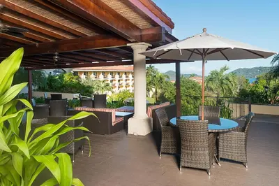 a patio with a table and chairs and an umbrella at Occidental Papagayo - Adults Only All Inclusive in Papagayo, Guanacaste