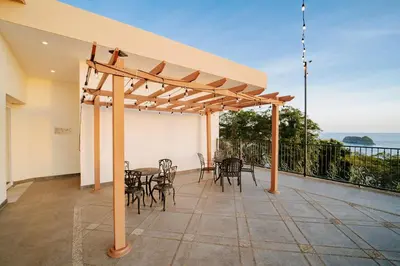 a patio with a table and chairs and a pergola at Parador Nature Resort and Spa in Manuel Antonio
