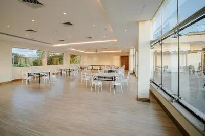 a large room with tables and chairs and windows at Parador Nature Resort and Spa in Manuel Antonio