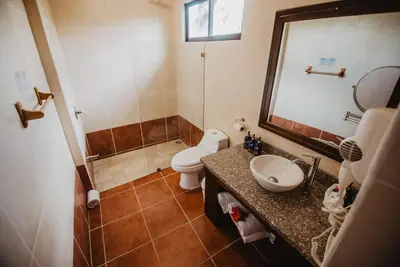 a bathroom with a toilet and a sink and a mirror at Hacienda Guachipelin Volcano Ranch Hotel & Hot Springs in Liberia