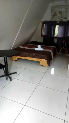 a bedroom with a bed and a chair in a attic at Hotel Monte Campana Heredia in Birrí
