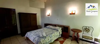 a bedroom with a bed and a table and a chair at Hotel Monte Campana Heredia in Birrí