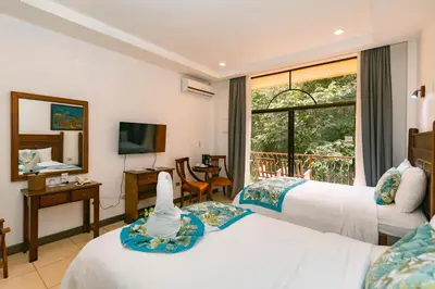 a hotel room with two beds and a window at Hotel San Bada Resort & Spa in Manuel Antonio