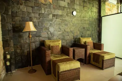 a room with chairs and a lamp and a stone wall at Hotel San Bada Resort & Spa in Manuel Antonio