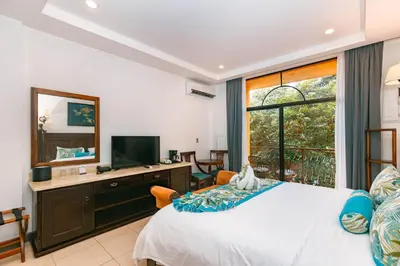 a bedroom with a bed and a tv and a window at Hotel San Bada Resort & Spa in Manuel Antonio