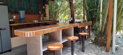 a wooden counter with stools in a room with trees at Mal Pais Surf Camp in Santa Teresa Beach