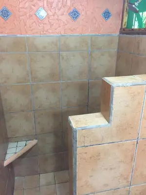 a bathroom with a tiled wall and a shelf at Mal Pais Surf Camp in Santa Teresa Beach