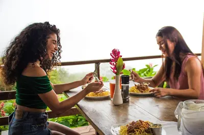 two women sitting at a table with plates of food at Adventure Park & Hotel Vista Golfo in Tajo Alto