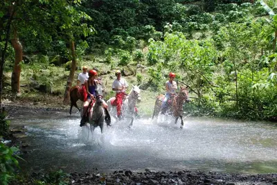 a group of people riding horses through a river at Adventure Park & Hotel Vista Golfo in Tajo Alto