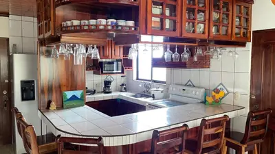 a kitchen with a white counter top and wooden cabinets at Las Pavitas Arenal Suites in Fortuna