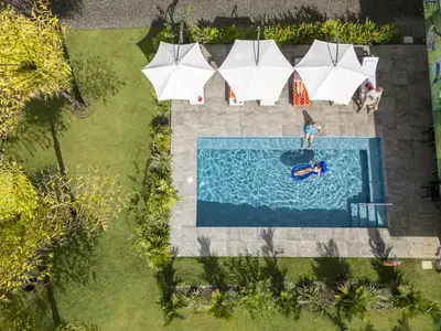 an overhead view of a person swimming in a pool with umbrellas at Junglebungalow in Platanillo