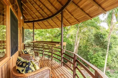 a porch of a cabin with chairs and a view of the forest at Junglebungalow in Platanillo