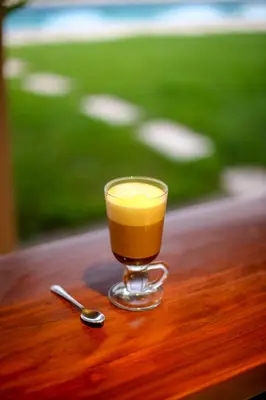 a glass of orange juice sitting on a table with a spoon at Casitas Sollevante Boutique Hotel in Montezuma