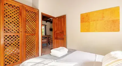 a bedroom with a white bed and a wooden cabinet at Bahia Esmeralda Boutique Hotel & Villas in Potrero