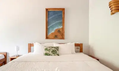 a bedroom with a white bed with a picture on the wall at Bahia Esmeralda Boutique Hotel & Villas in Potrero