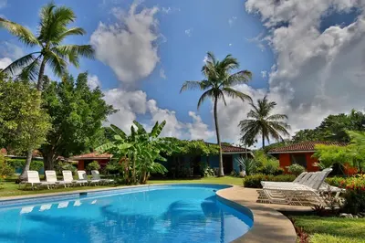 a swimming pool with lounge chairs and palm trees at Bahia Esmeralda Boutique Hotel & Villas in Potrero