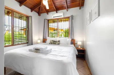 a bedroom with a large white bed with two windows at Bahia Esmeralda Boutique Hotel & Villas in Potrero