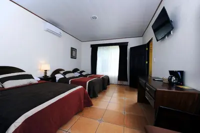 a hotel room with two beds and a flat screen tv at Hotel Robledal in Alajuela City