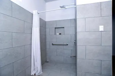 a shower with a shower curtain in a bathroom at Hotel Robledal in Alajuela City