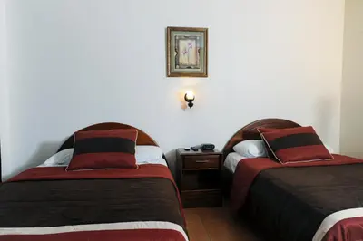 a hotel room with two beds and a night stand at Hotel Robledal in Alajuela City