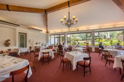 a dining room with white tables and chairs and people at Hotel Bougainvillea San José in Santo Domingo