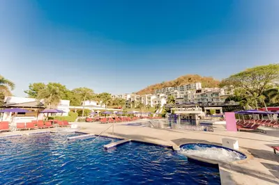 a swimming pool with a boat in the water at Planet Hollywood Costa Rica by Royalton, An Autograph Collection All-Inclusive Resort in Papagayo, Guanacaste