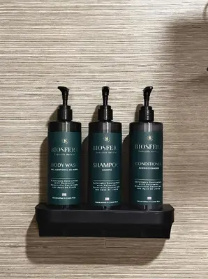 three bottles of shampoo sitting on a black shelf at Villa Tucan in Fortuna