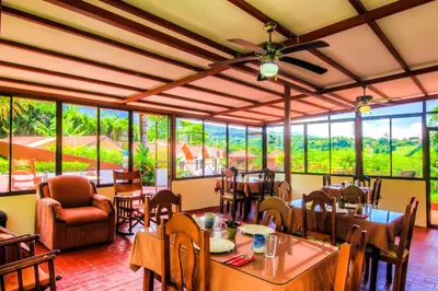 a restaurant with tables and chairs and large windows at Hotel Mango Valley in Grecia