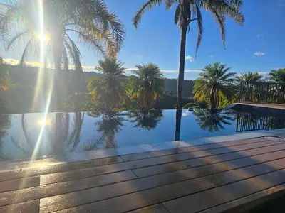 a pool with palm trees and the sun shining on the water at Hotel Mango Valley in Grecia