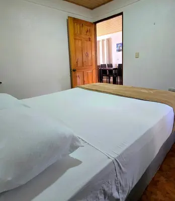 a bedroom with a large white bed with a wooden door at Casa Cattleya - Monteverde, Costa Rica in Monteverde Costa Rica