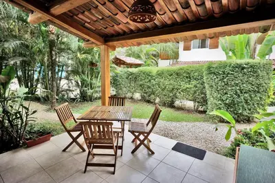 a wooden table and chairs under a wooden pergola at Costa Riki Apartments in Santa Teresa Beach