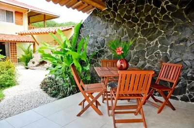 a wooden table with four chairs and a vase on it at Costa Riki Apartments in Santa Teresa Beach