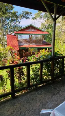 a red bench in a garden with a gazebo at Vista Turrialba Lodge in Turrialba